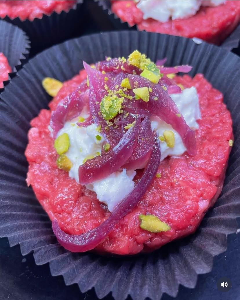 Un primo piano di un cupcake rosa con cipolle e pistacchi sopra