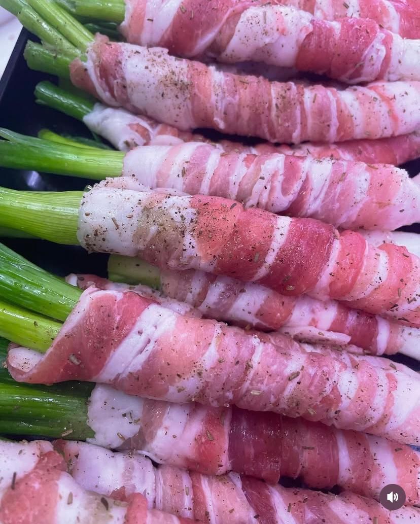 Un primo piano di asparagi avvolti nella pancetta su un piatto.