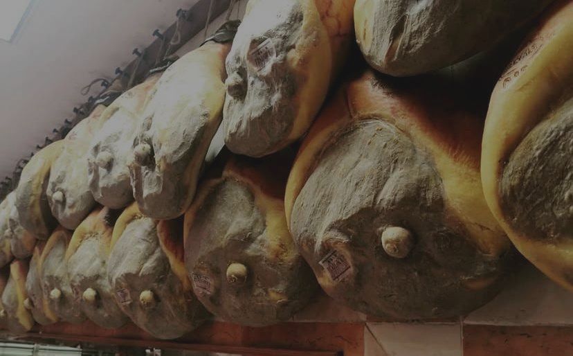 Un mucchio di prosciutti è appeso a un muro.