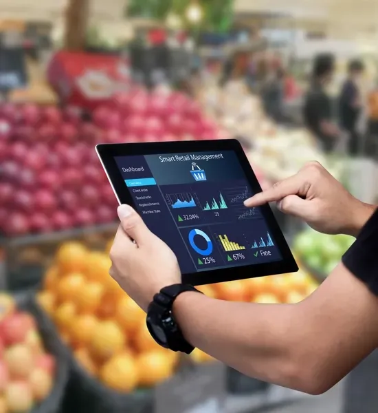Hands using a tablet with analytics dashboard in a produce market aisle
