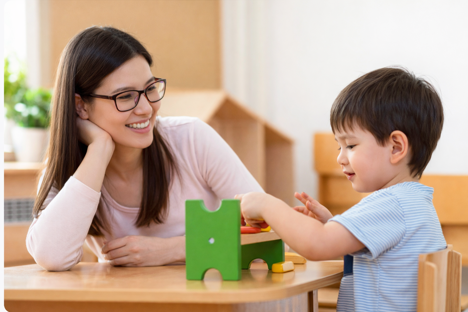 Woman and child building with wooden blocks at a table. Child focused; woman observing. Bright, colorful blocks.