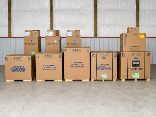 Stacked cardboard boxes in a warehouse, with large shipping cartons on the floor and smaller boxes on top.