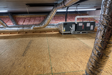 Insulated attic HVAC ducts and vents above plywood flooring in a crawlspace