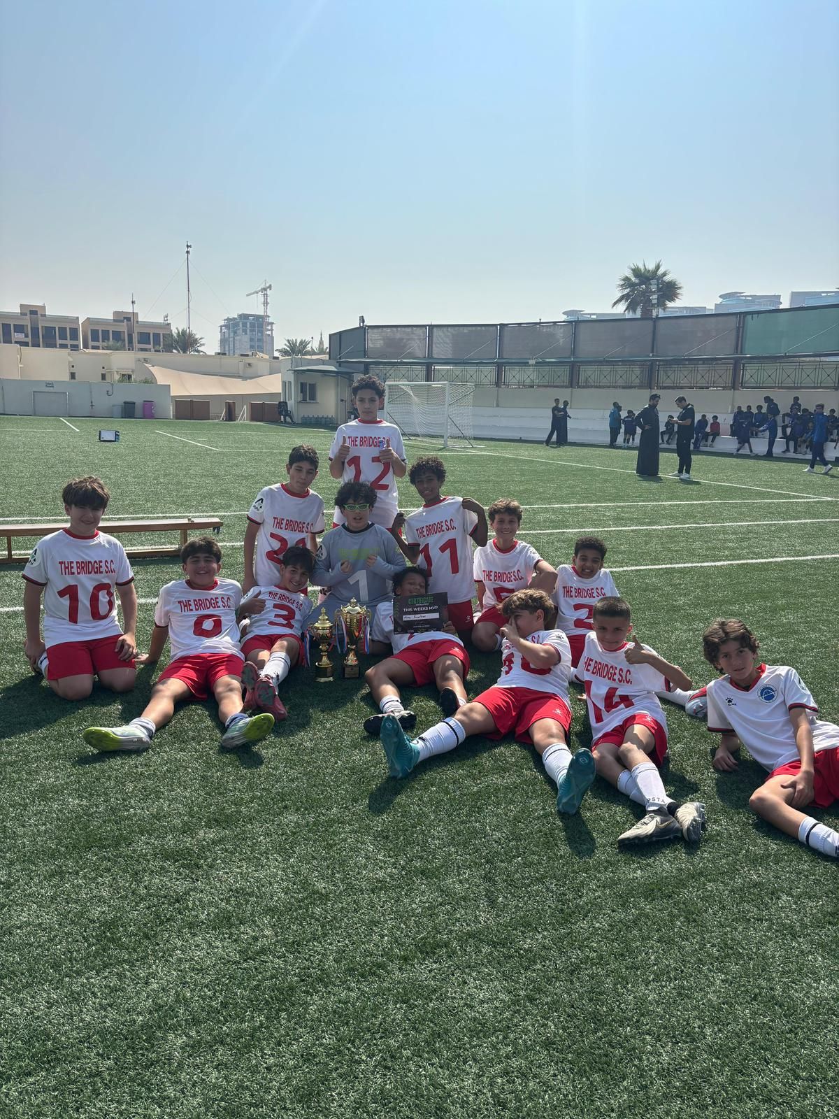Soccer or football team  on a green field celebrating the league championship. They are posing and smiling in the sunlight. They hace won the competition. 