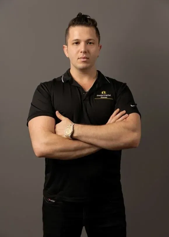 A man in a black shirt is standing with his arms crossed.