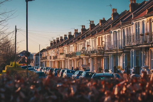 A row of houses with cars parked in front of them on a sunny day.