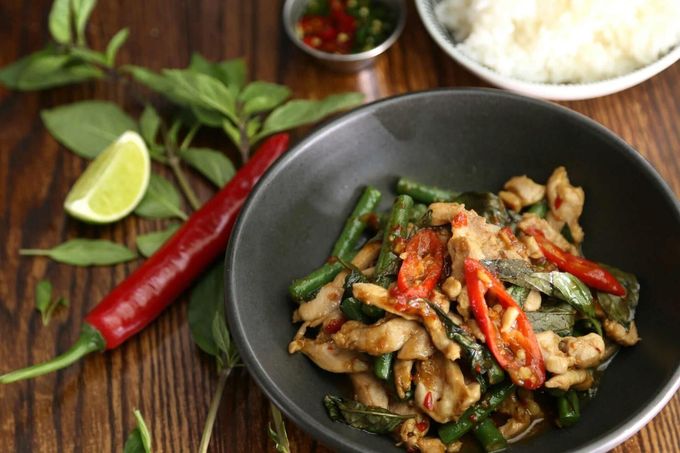 A Black Bowl Filled With Chicken And Green Beans On A Wooden Table — Mod Thai Nelson Bay In Nelson Bay, NSW