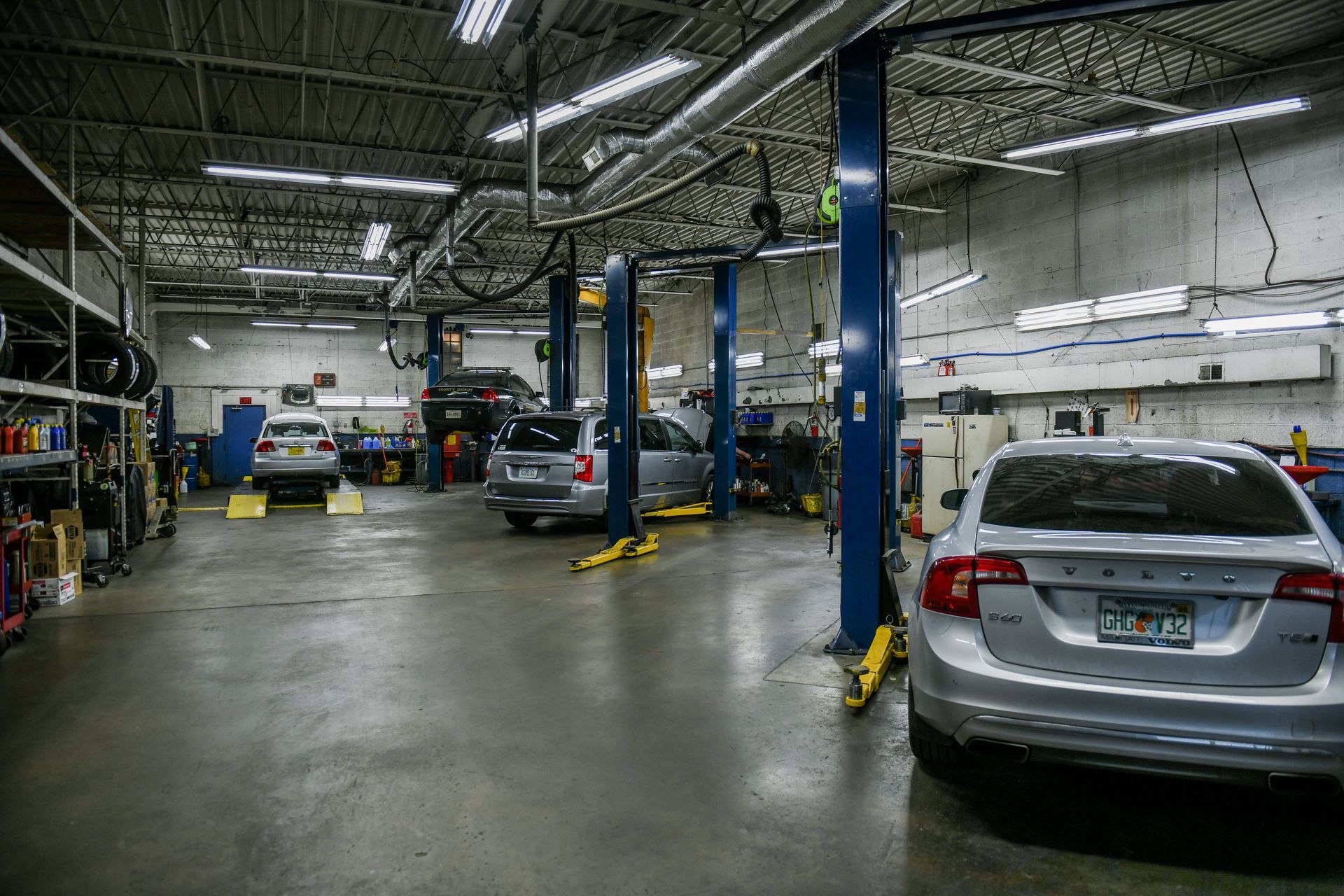Auto repair shop with cars on lifts and parked vehicles in a large industrial garage