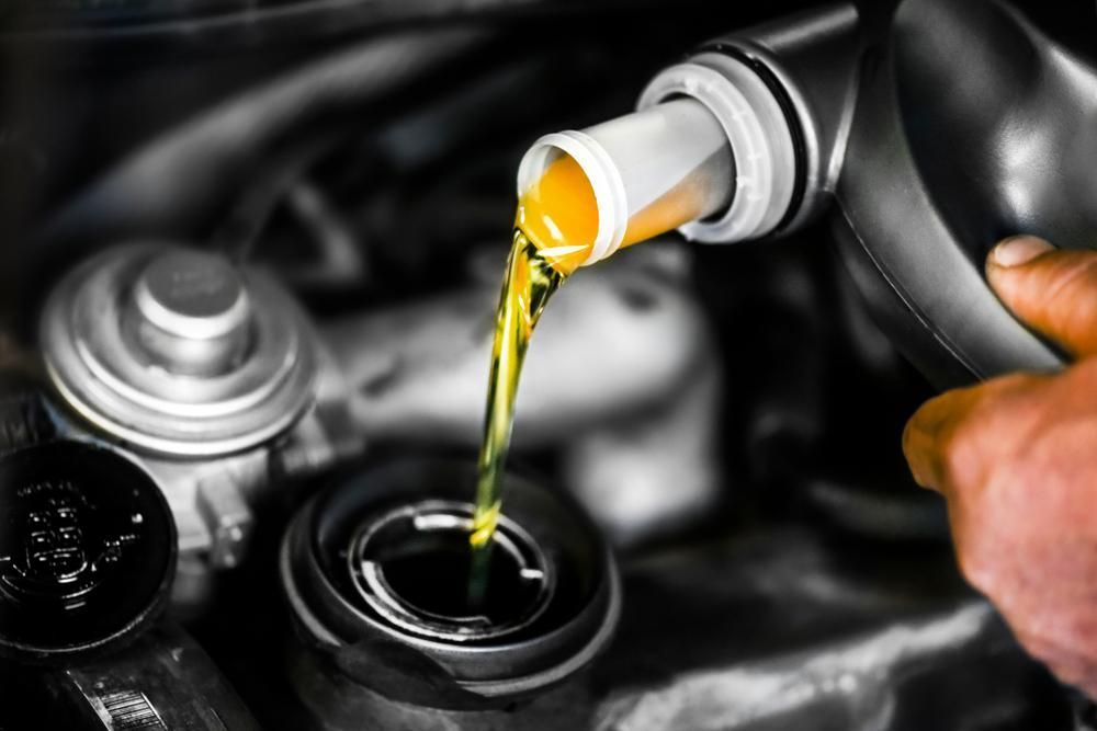 A Person is Pouring Oil Into a Car Engine — Ballina Bearing Supplies In Byron, NSW