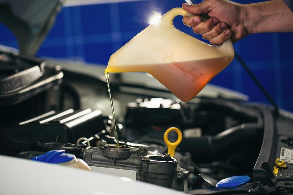 A Person is Pouring Oil Into a Car Engine — Ballina Bearing Supplies In Grafton, NSW