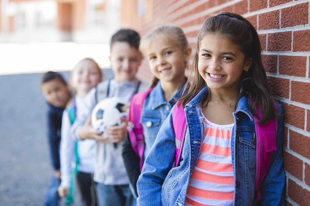 A group of children are standing in front of a brick building.