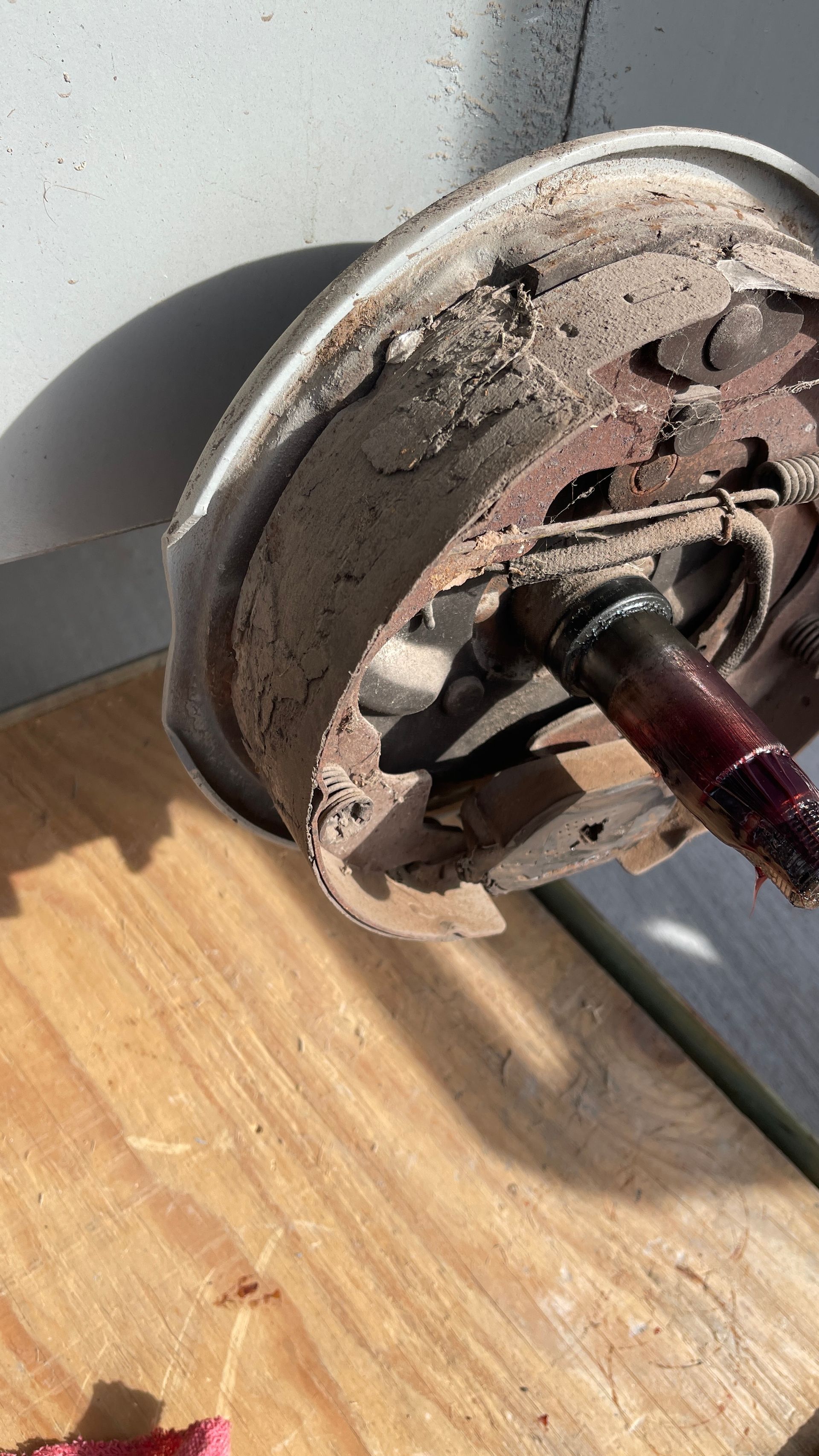 A dirty brake drum and axle on a wooden surface, showing wear and tear.