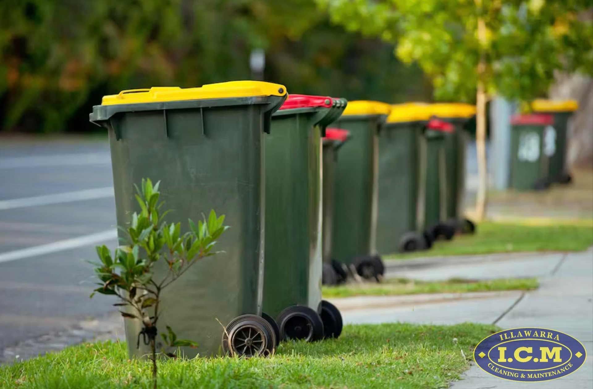 A Row Of Garbage Cans Are Lined Up On The Side Of The Road — Illawarra Cleaning & Maintenance In Dapto, NSW