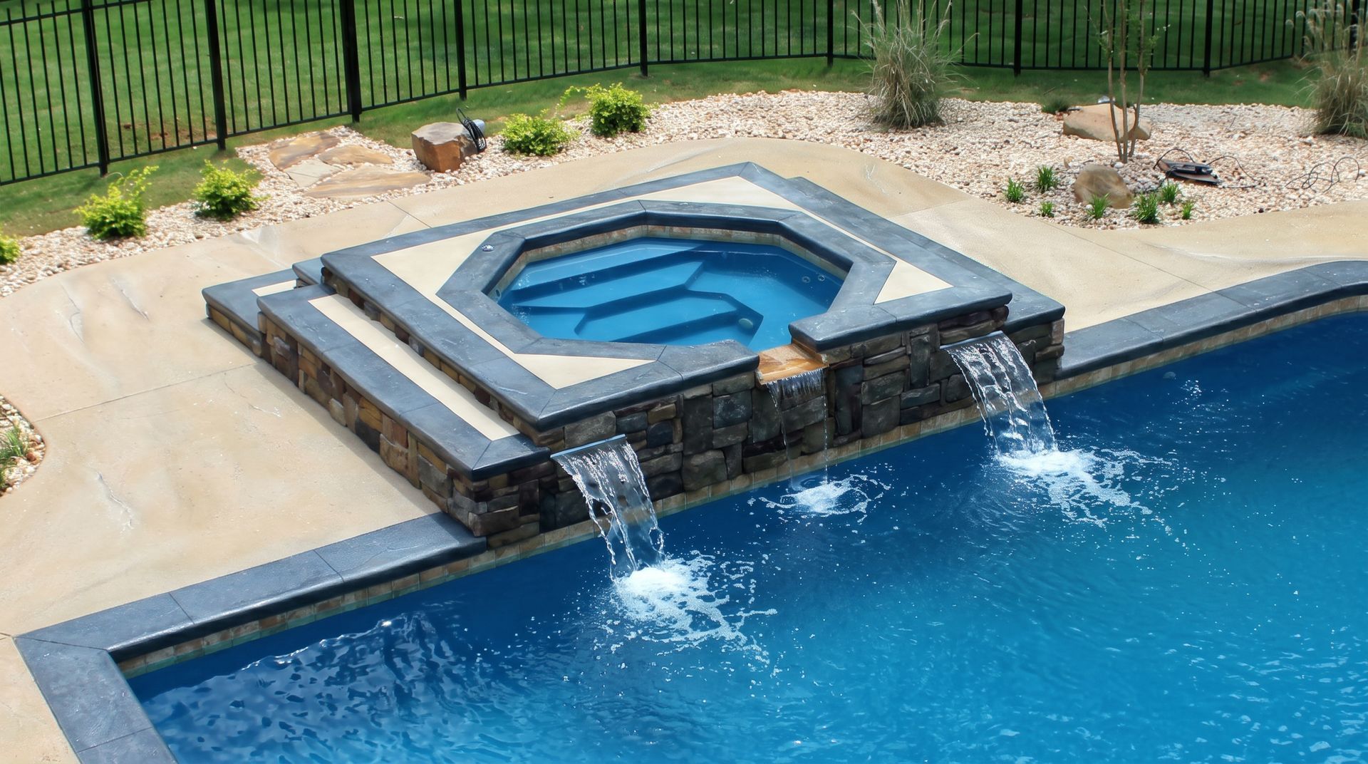 Modern backyard pool with raised hot tub and two cascading waterfalls into blue water