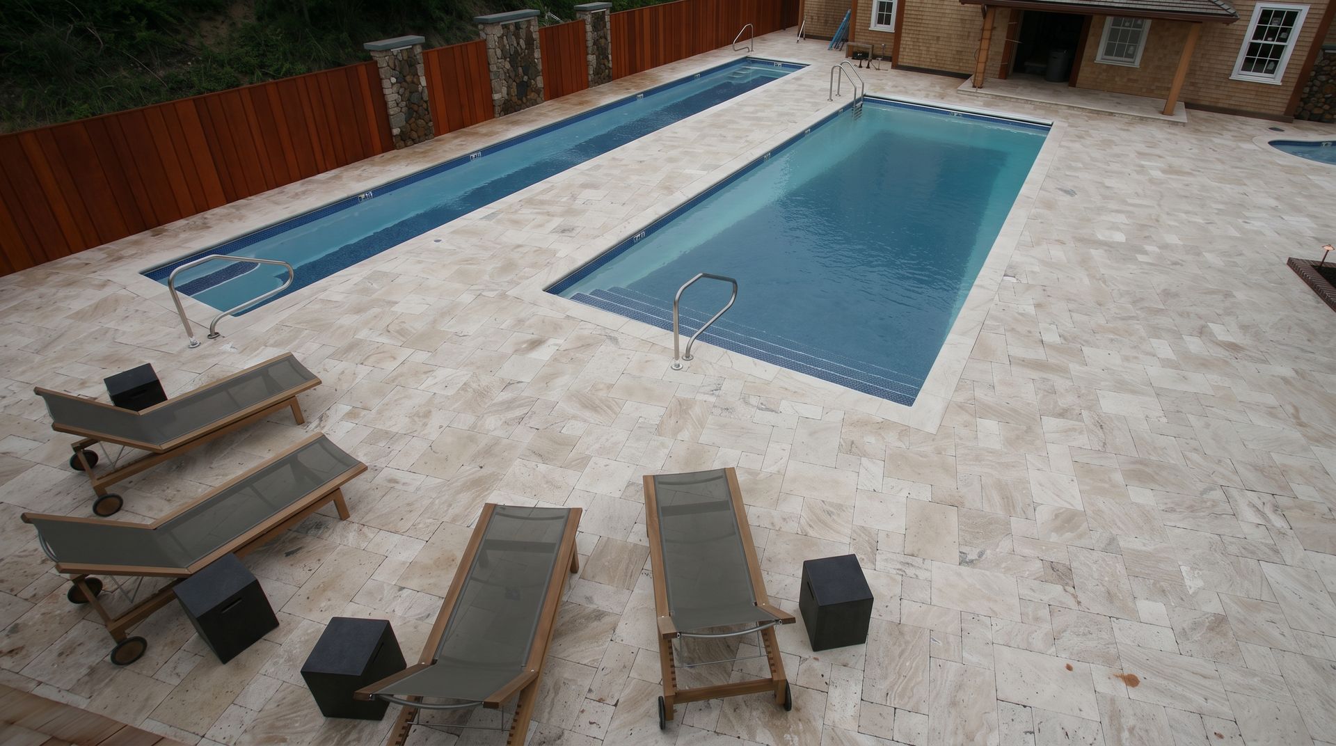 Courtyard with a swimming pool, hot tub, lounge chairs, and a dining table on a stone patio