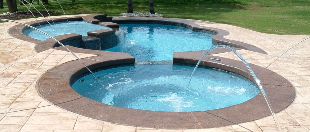 Backyard swimming pool with two round blue spa pools linked by a narrow bridge