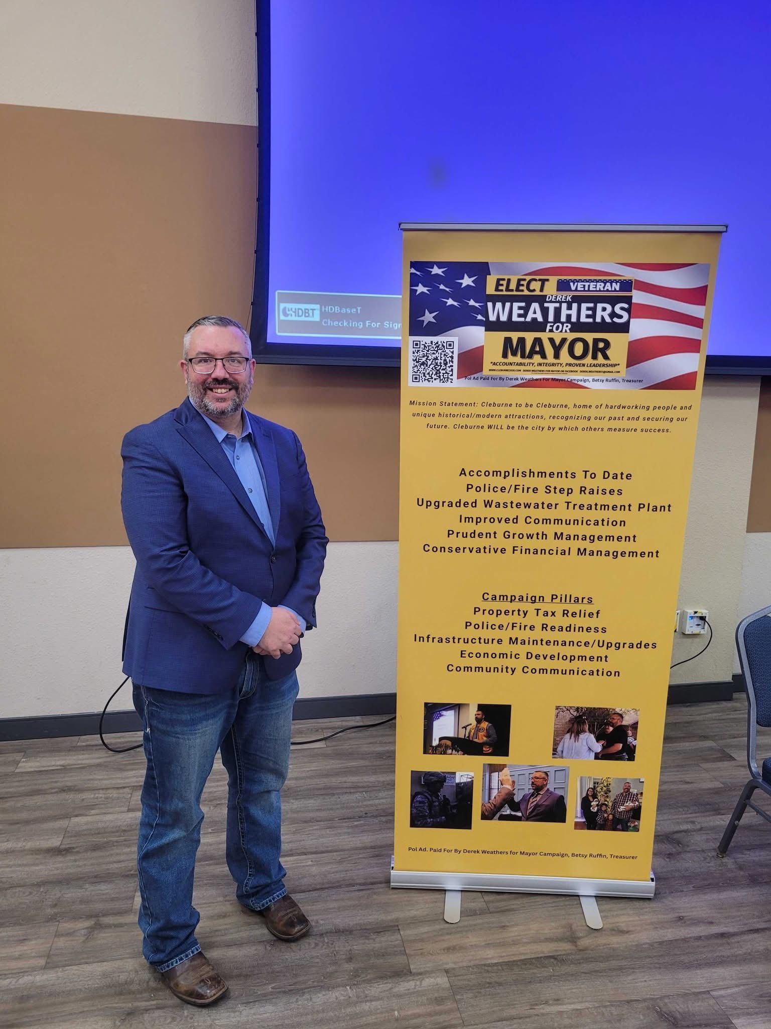 Man standing beside a yellow “Weather Mayor” poster in a conference room
