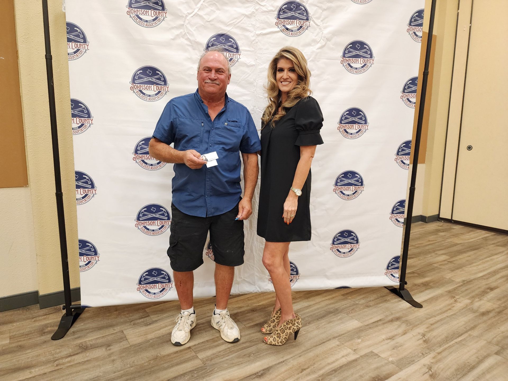 A man and a woman are posing for a picture in front of a backdrop.