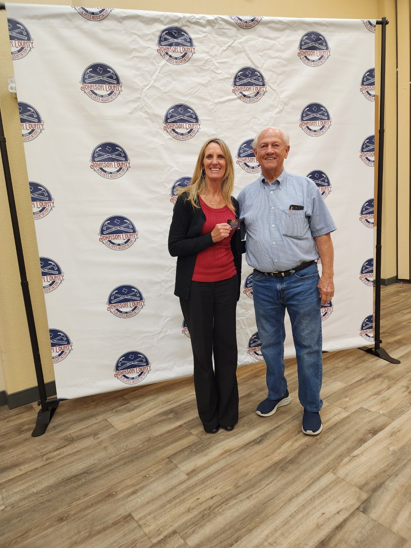 A man and a woman are posing for a picture in front of a backdrop.