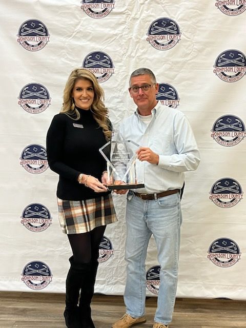 A man and a woman are standing next to each other holding a trophy.