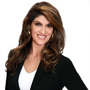 A woman in a black jacket and white shirt is smiling for the camera.