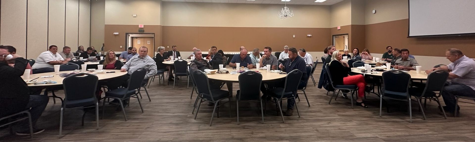 A group of people are sitting at tables in a conference room.