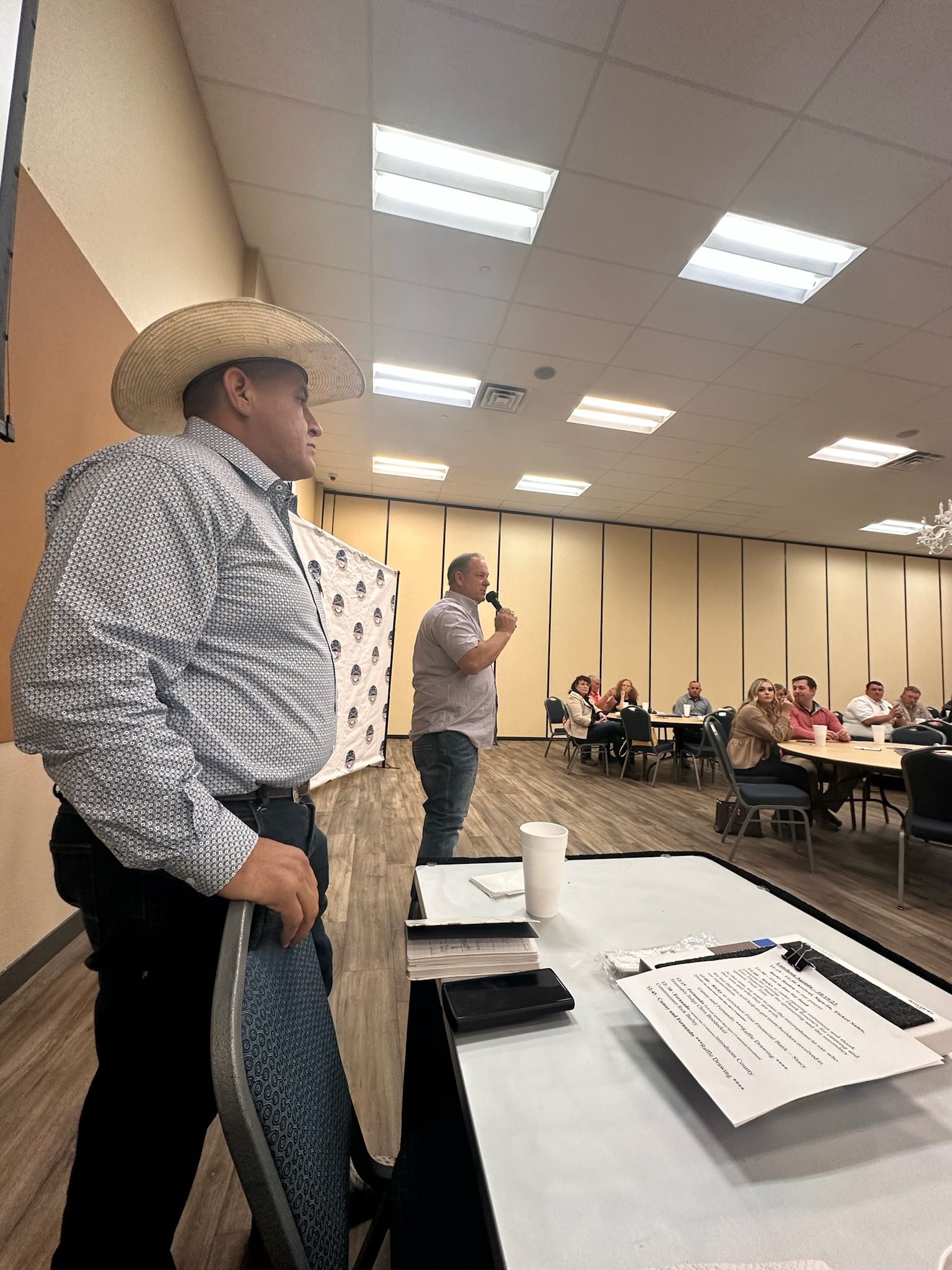 A man in a cowboy hat is standing in front of a group of people.