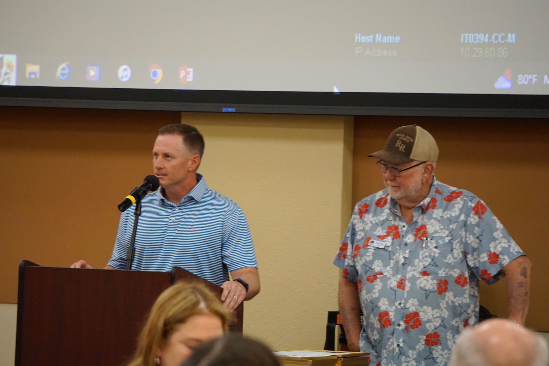 Two men are standing next to each other at a podium talking into microphones.