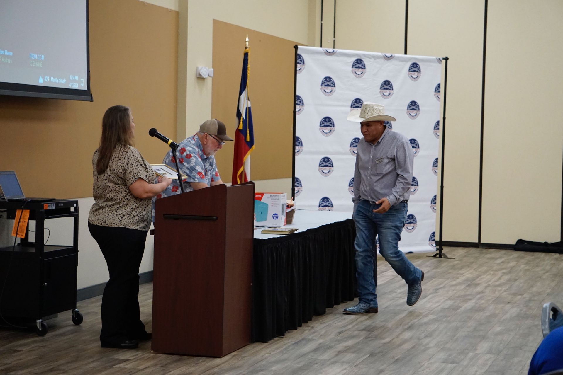 A man in a cowboy hat is standing in front of a podium.