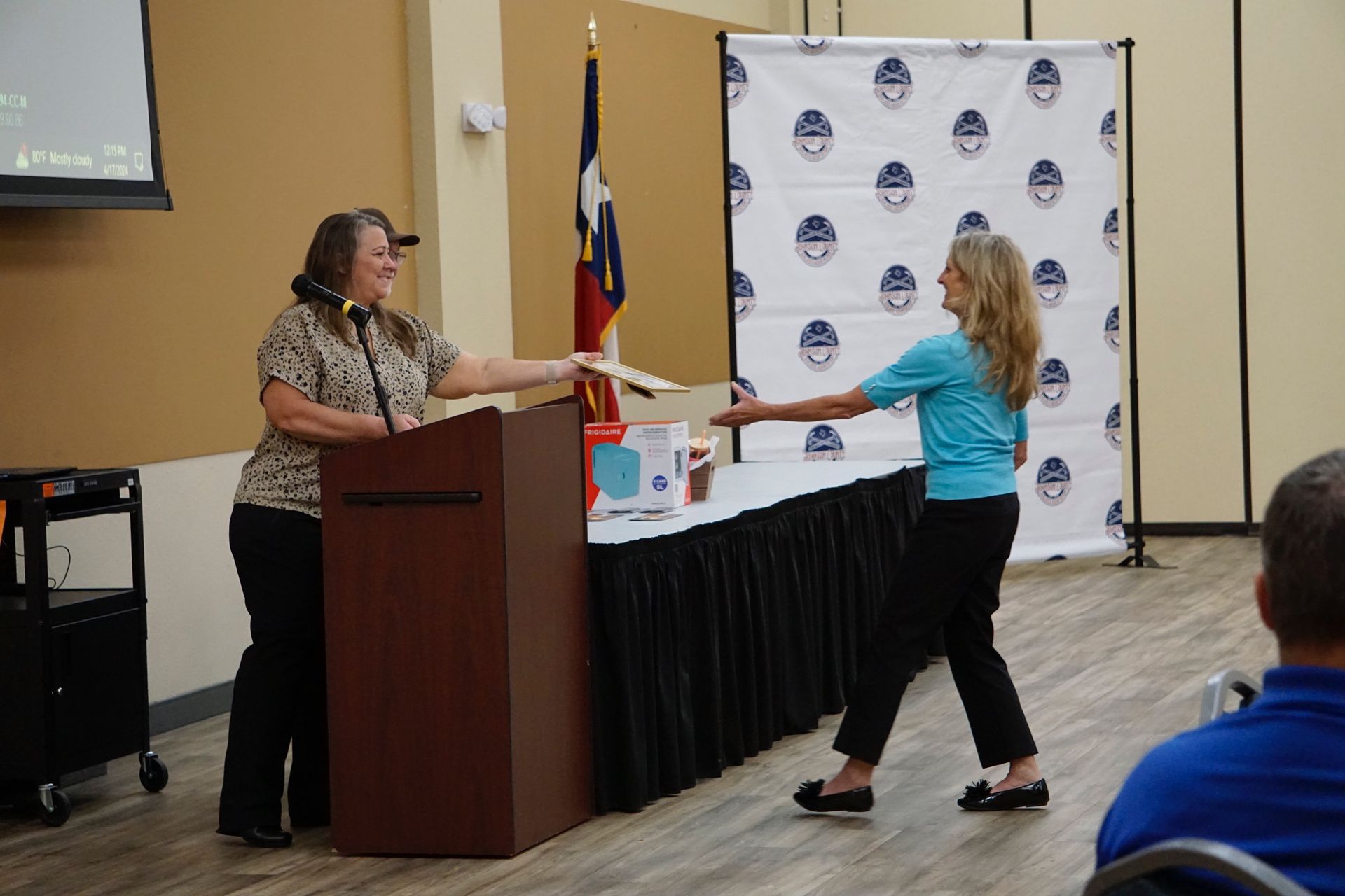 A woman is standing at a podium giving a certificate to another woman.