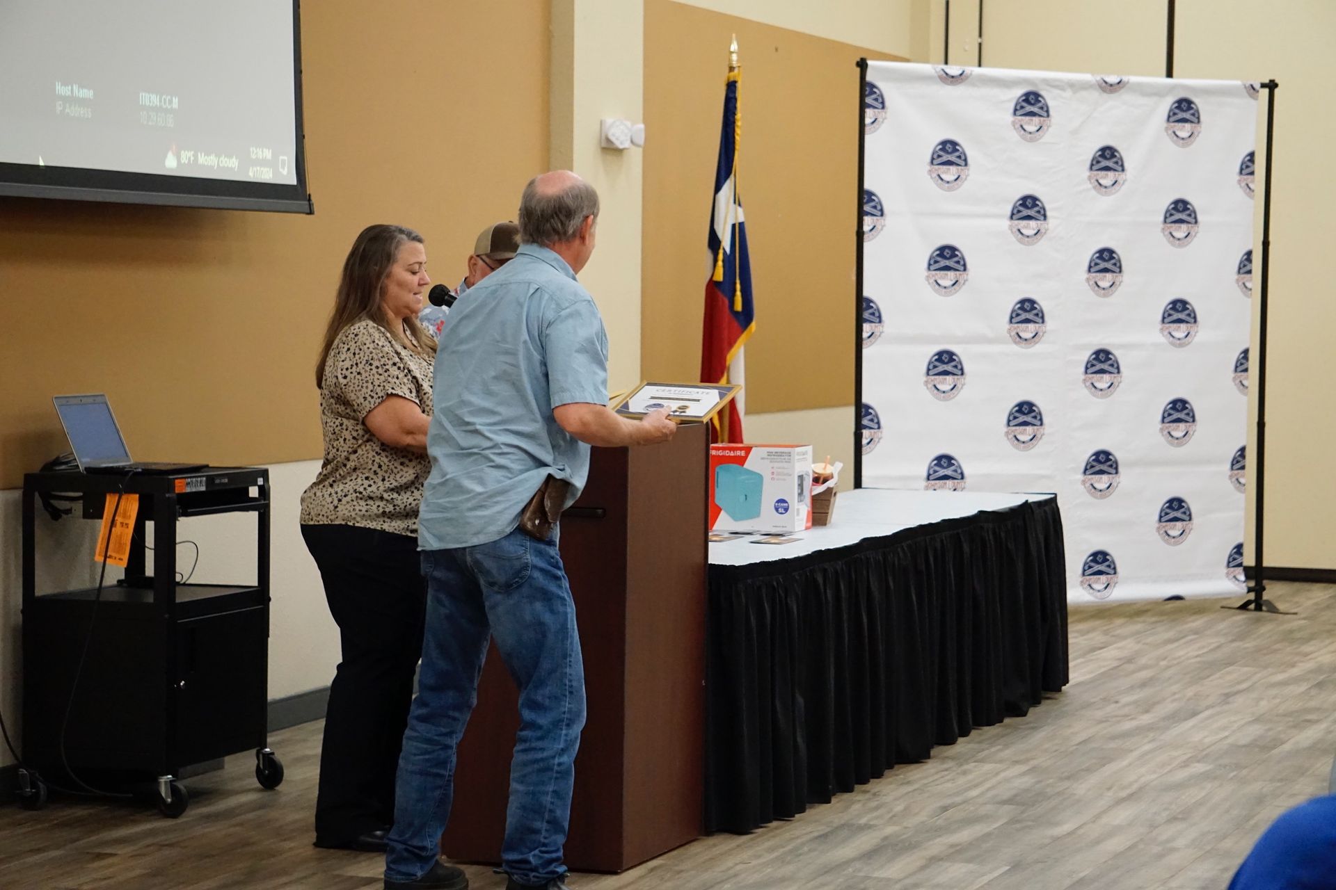 A man and a woman are standing in front of a podium in a room.