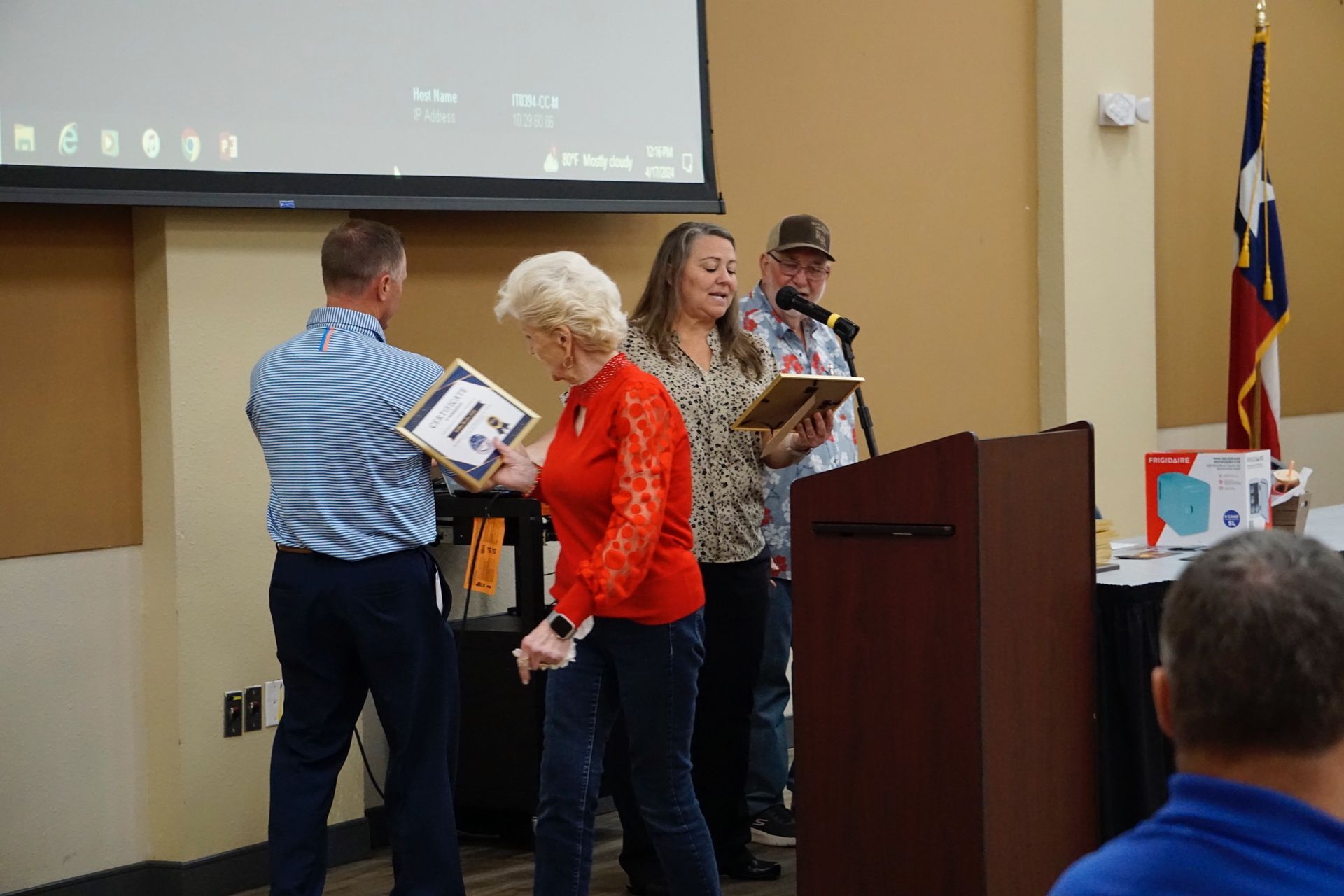 A group of people are standing around a podium holding awards.