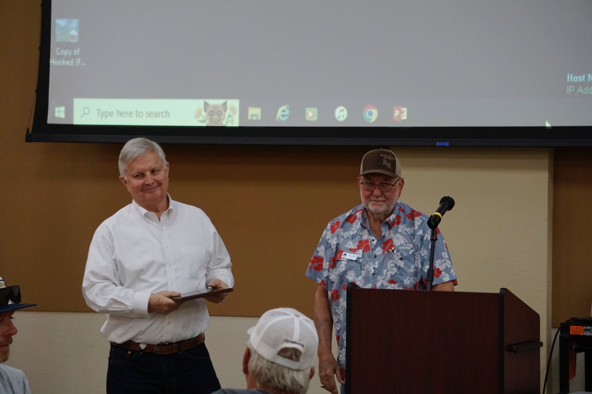 Two men are standing next to each other in front of a podium.