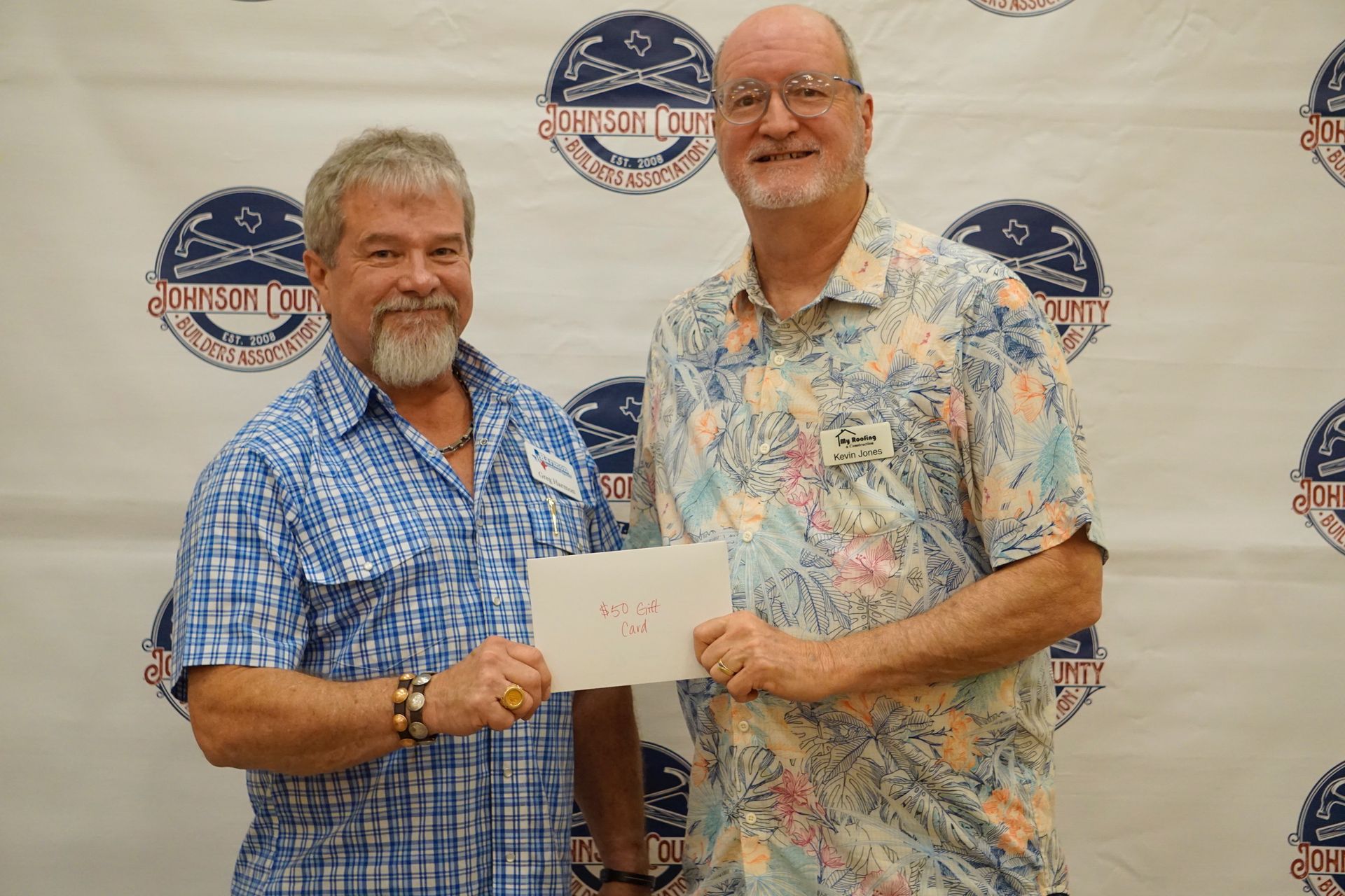 Two men are standing next to each other holding a check.