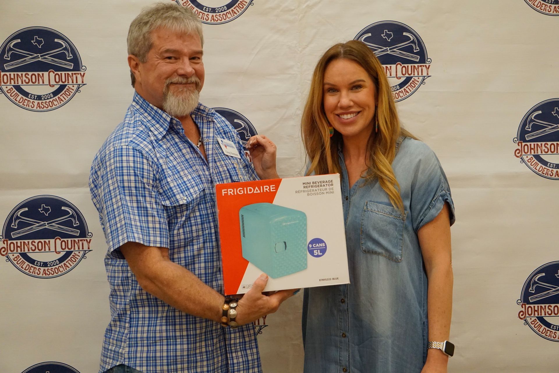 A man and a woman are standing next to each other holding a box.
