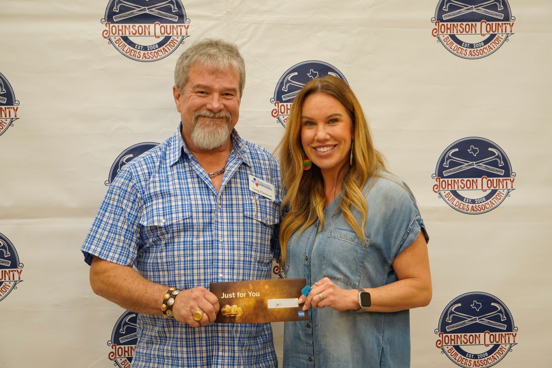 A man and a woman are standing next to each other holding a check.