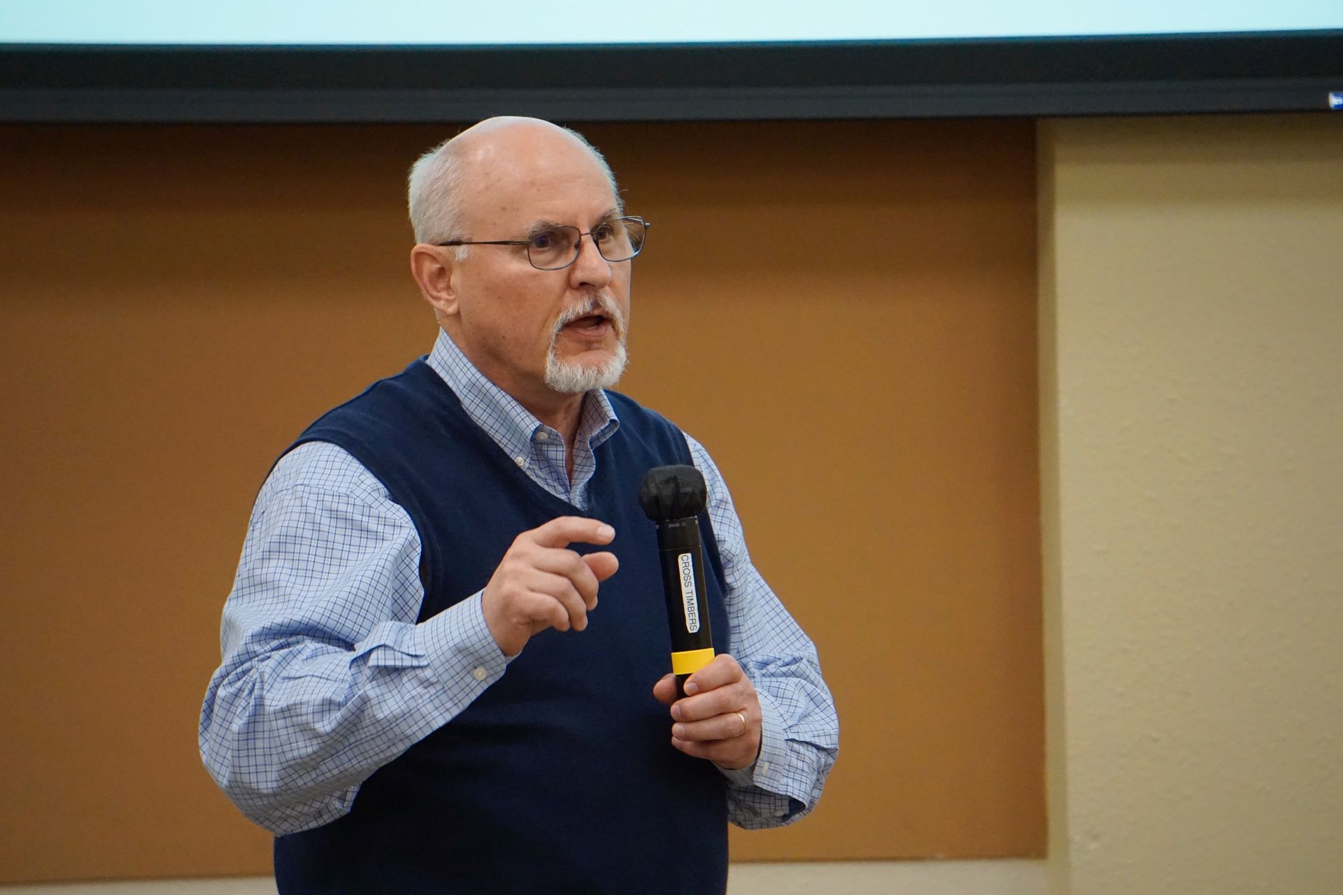 A man is holding a microphone and giving a presentation.