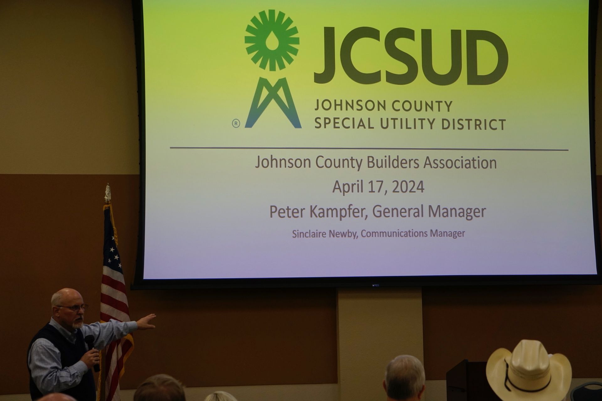 A man is giving a presentation in front of a screen that says johnson county special utility district
