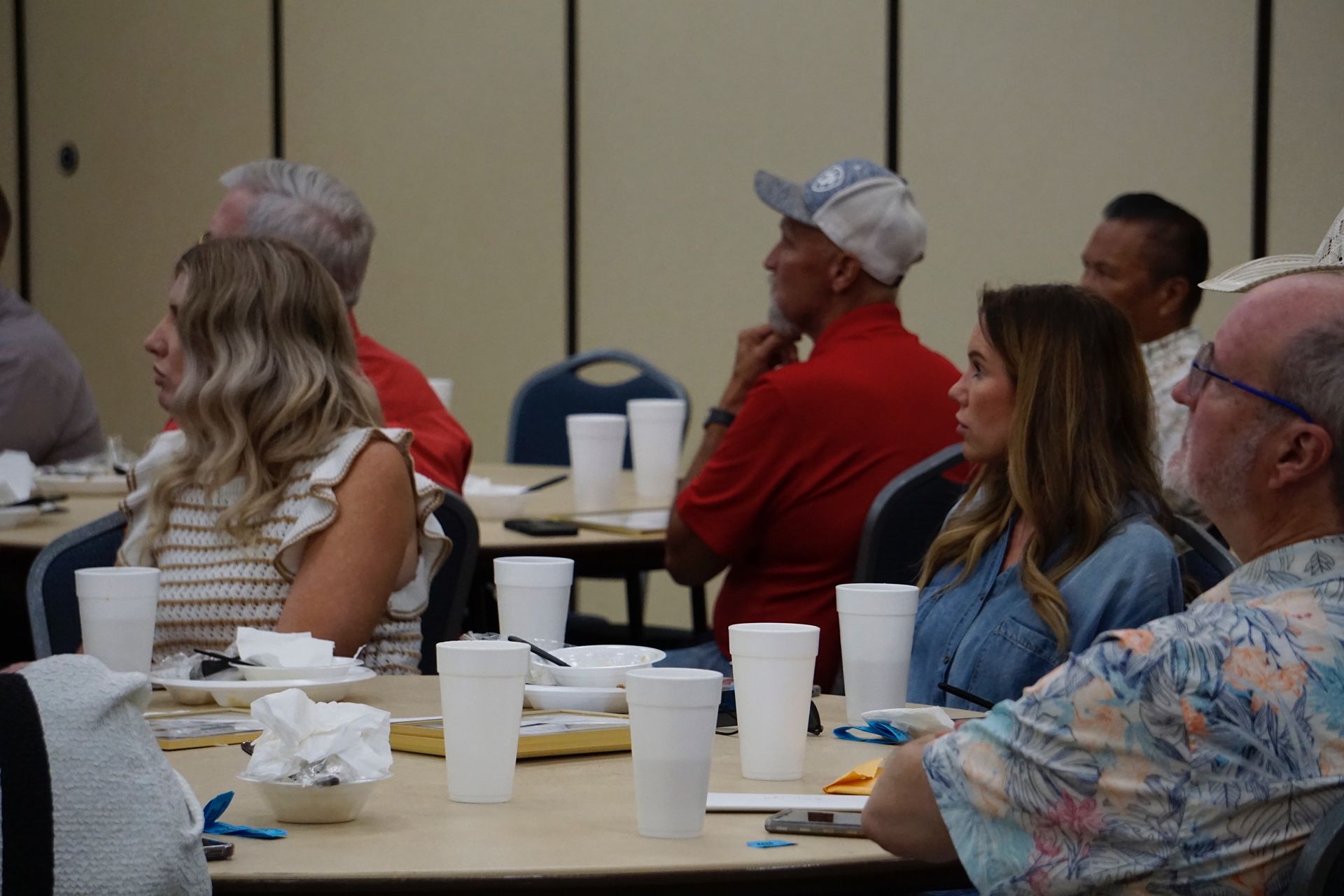 A group of people are sitting at tables with cups of coffee.