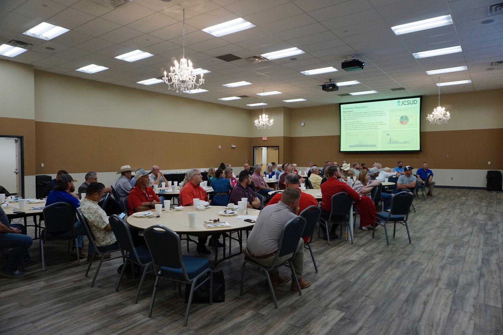 A group of people are sitting at tables in a large room.