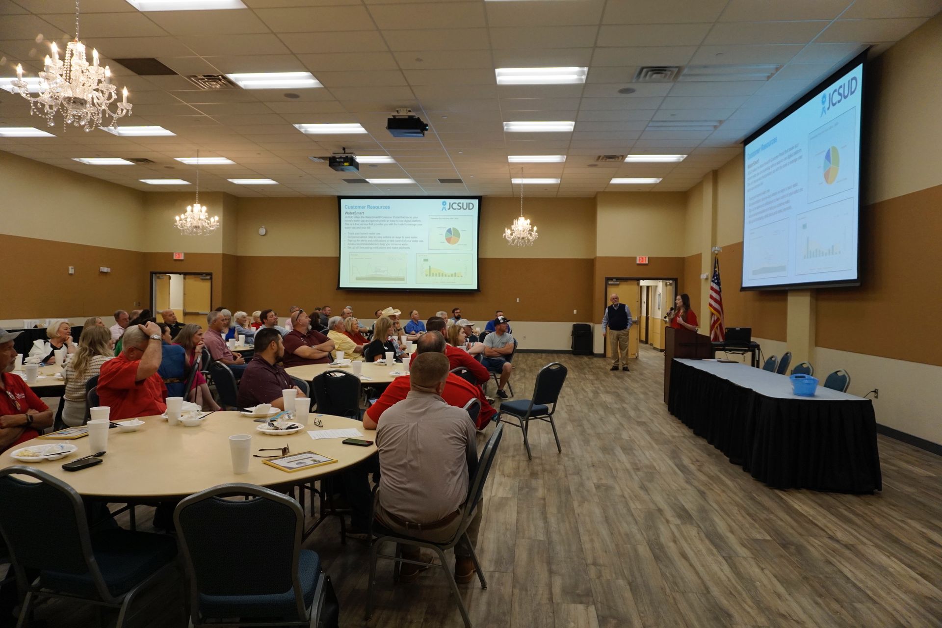 A large room filled with people sitting at tables and chairs.