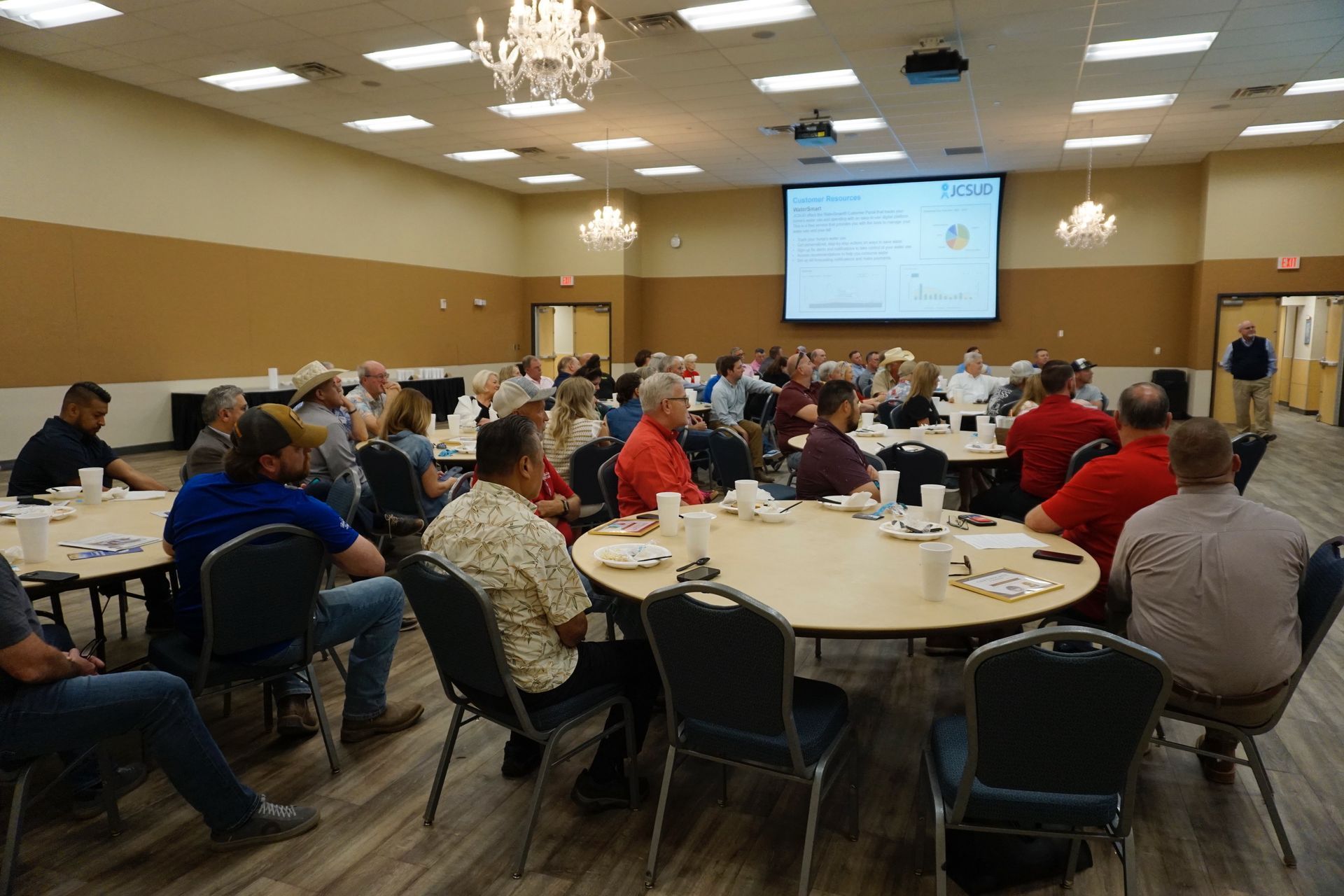 A large group of people are sitting at tables in a large room.