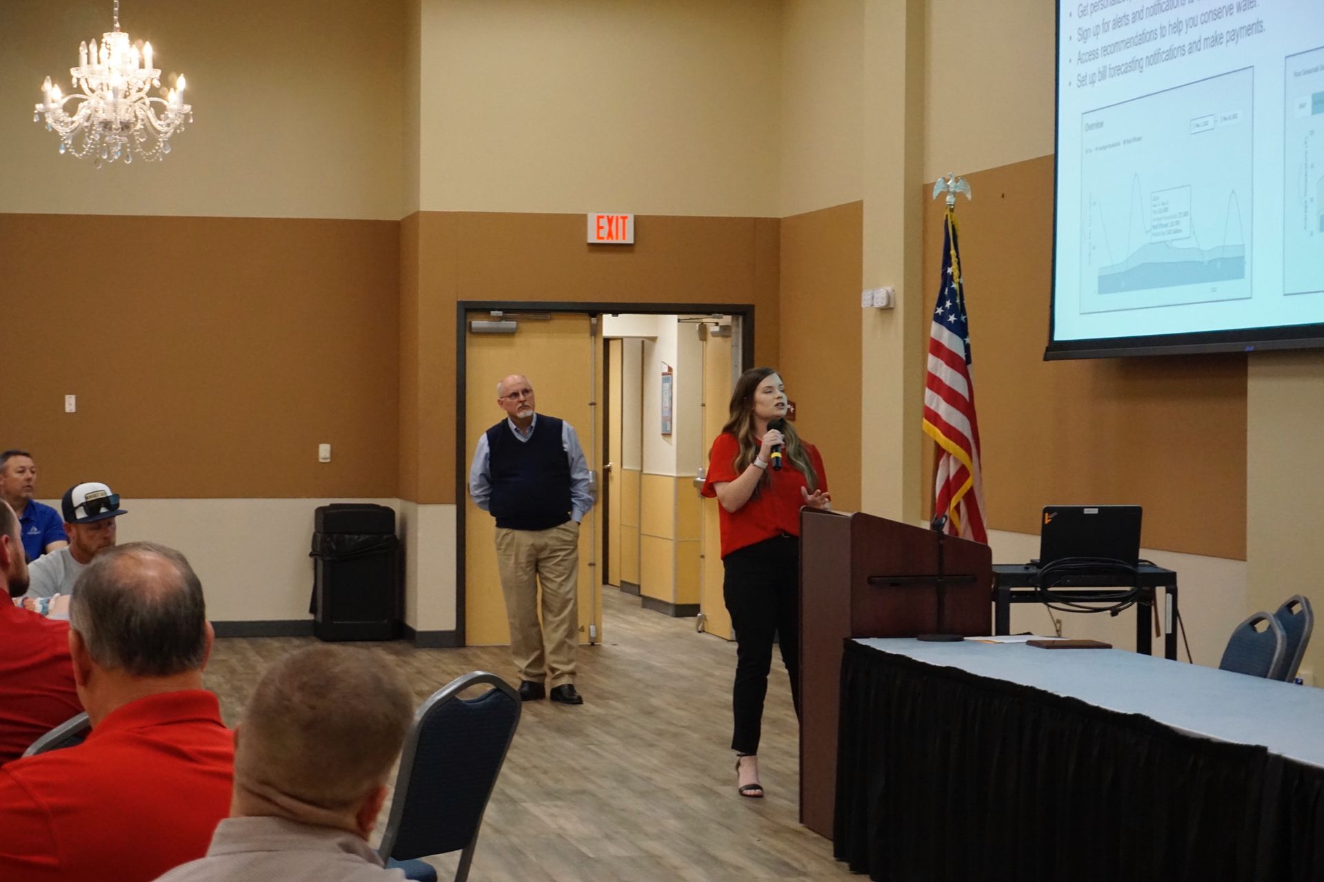 A woman is standing at a podium giving a presentation to a group of people.
