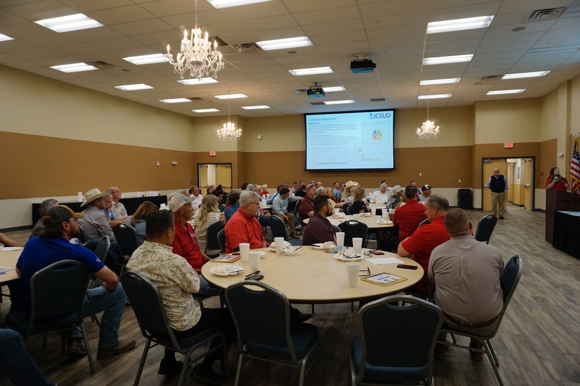 A large group of people are sitting at tables in a large room.