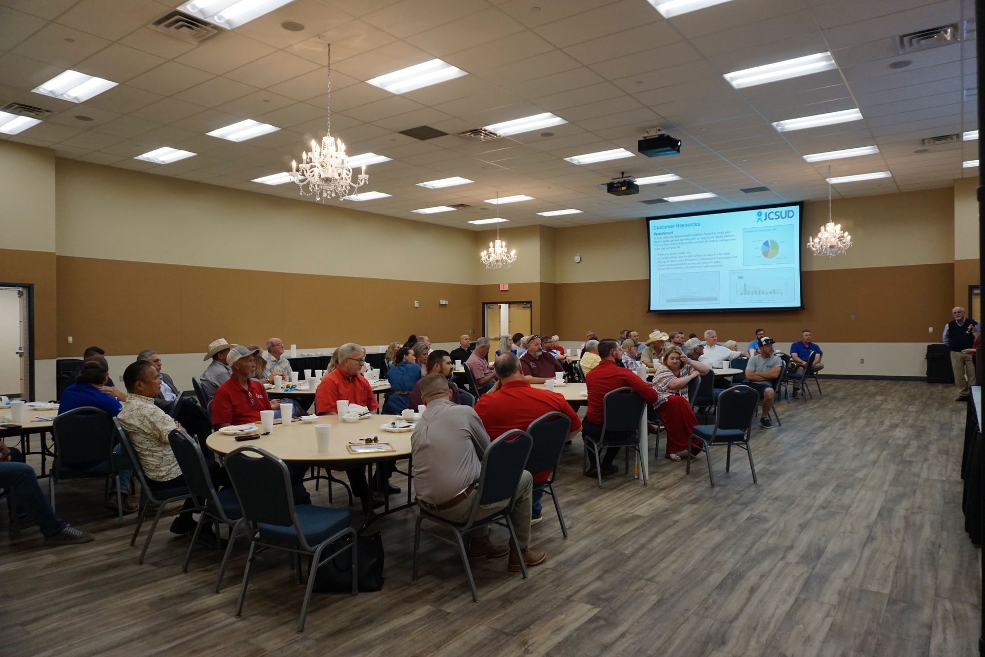 A group of people are sitting at tables in a large room.