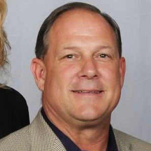 A man in a suit and tie is smiling for the camera.