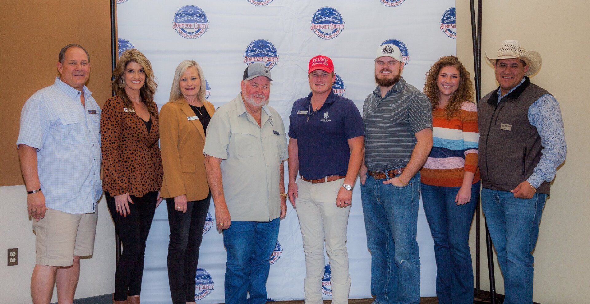 A group of people standing next to each other in front of a wall.