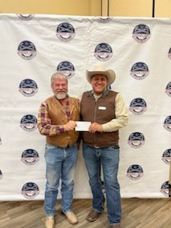 Two men are standing next to each other in front of a wall holding a check.