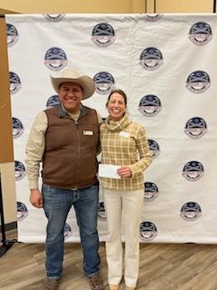 A man in a cowboy hat is standing next to a woman holding a check.