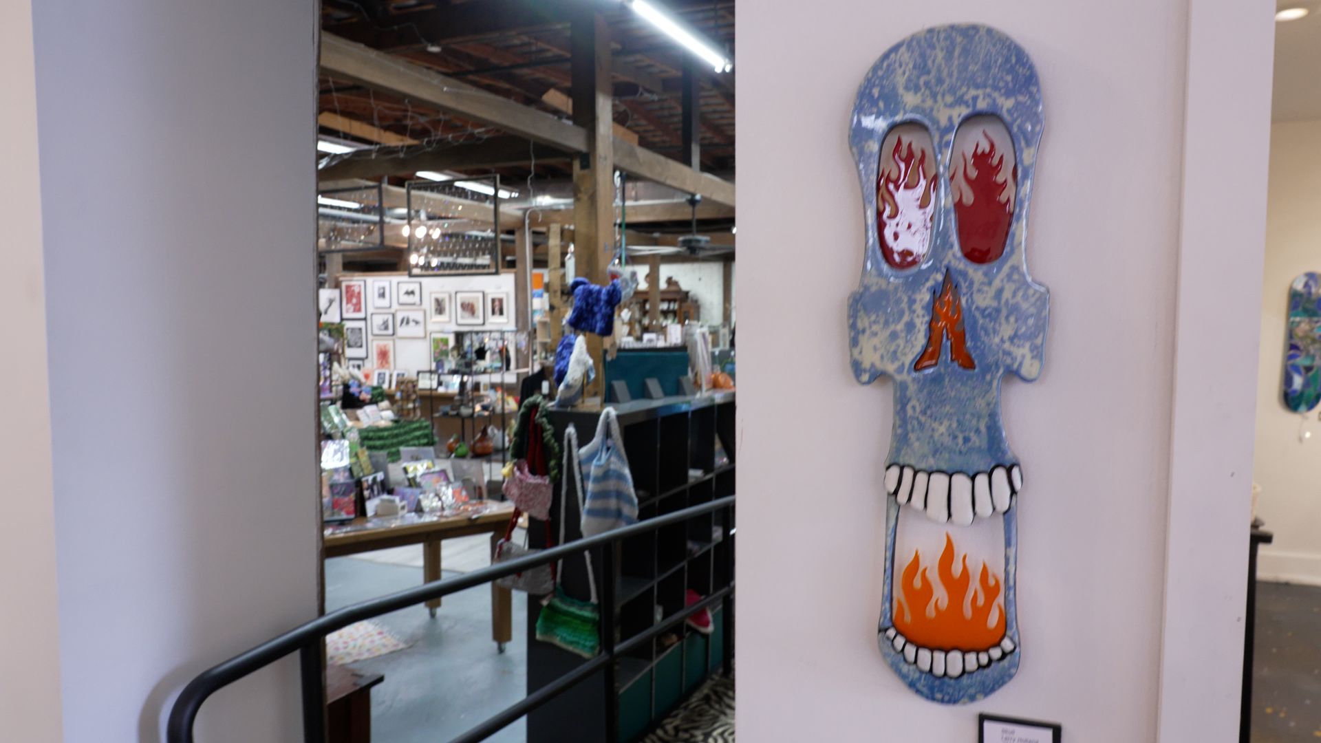 Colorful skull wall art in a store aisle, with red, blue, and orange details.